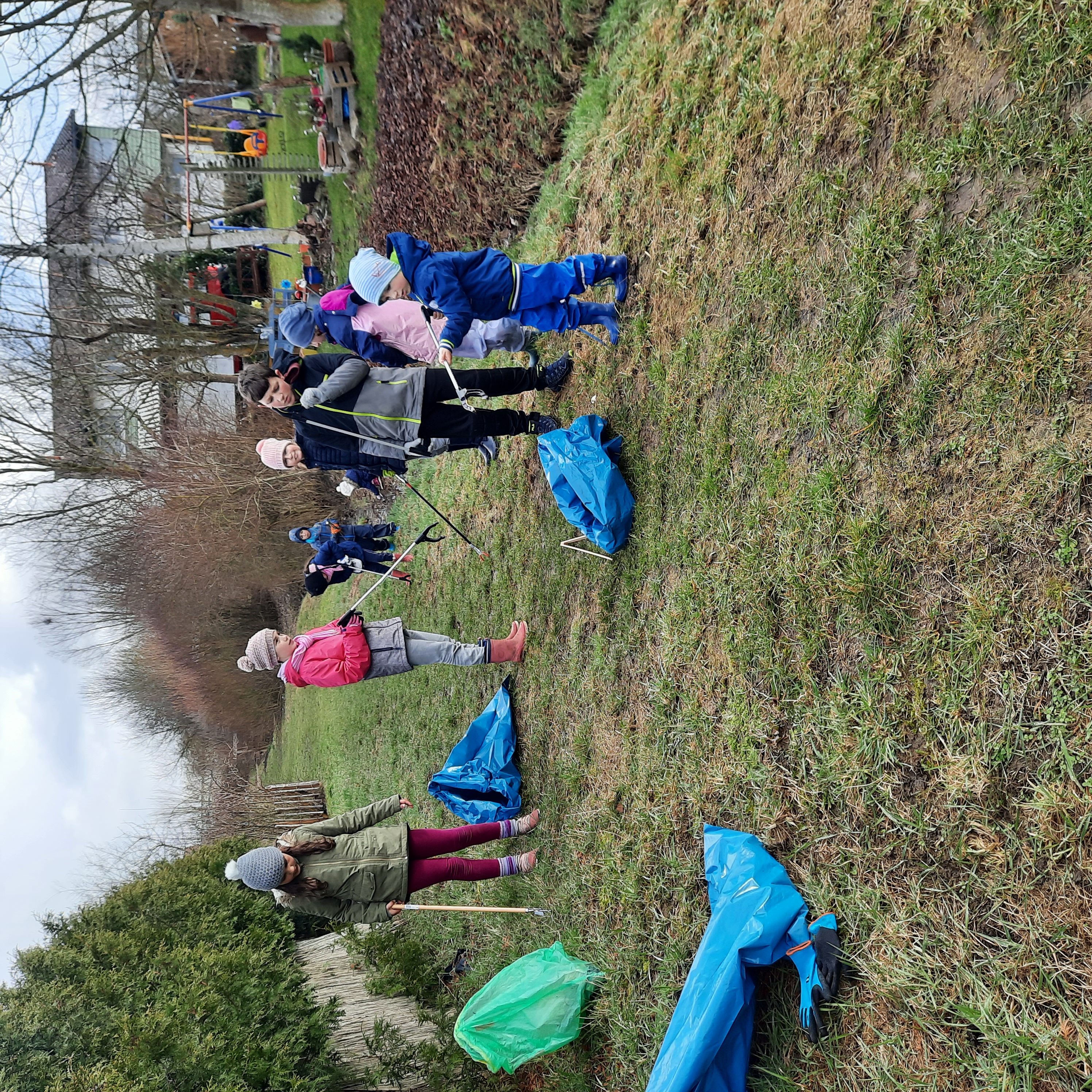 Einige Kinder mit Müllzangen und Säcken beim Sammeln